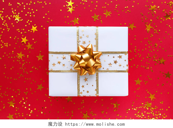 红色桌子上的纸盒白色礼品盒，金色蝴蝶结，红色背景的星星.